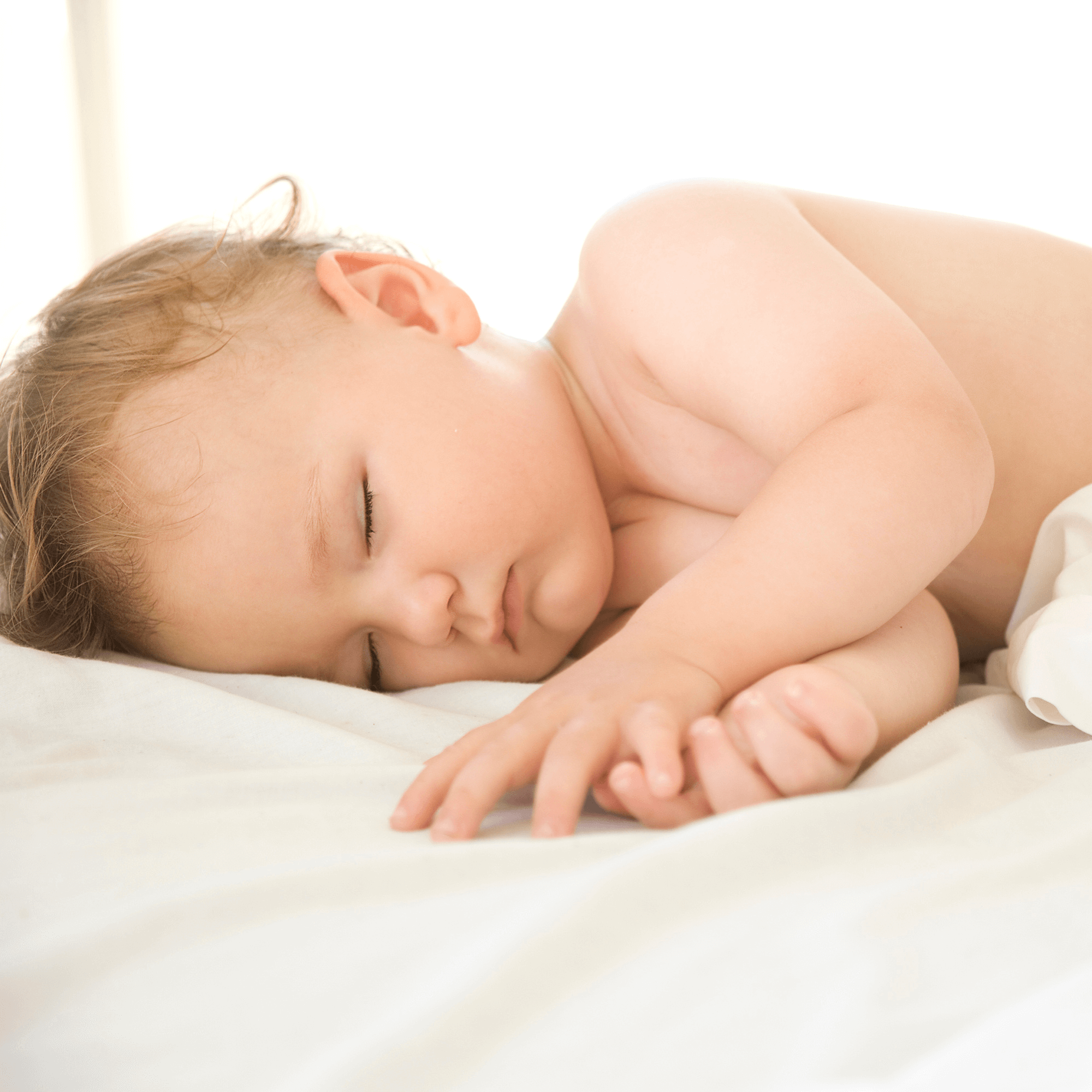 Toddler boy lying asleep in the cot on white Micro-Fresh cot bed sheets | Cot Bed Bedding | Baby Bedding - Clair de Lune UK