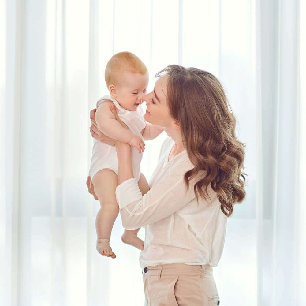 Mum holding baby by a window | Easter Gift Guide | Parenting & Buying Guides - Clair de Lune UK