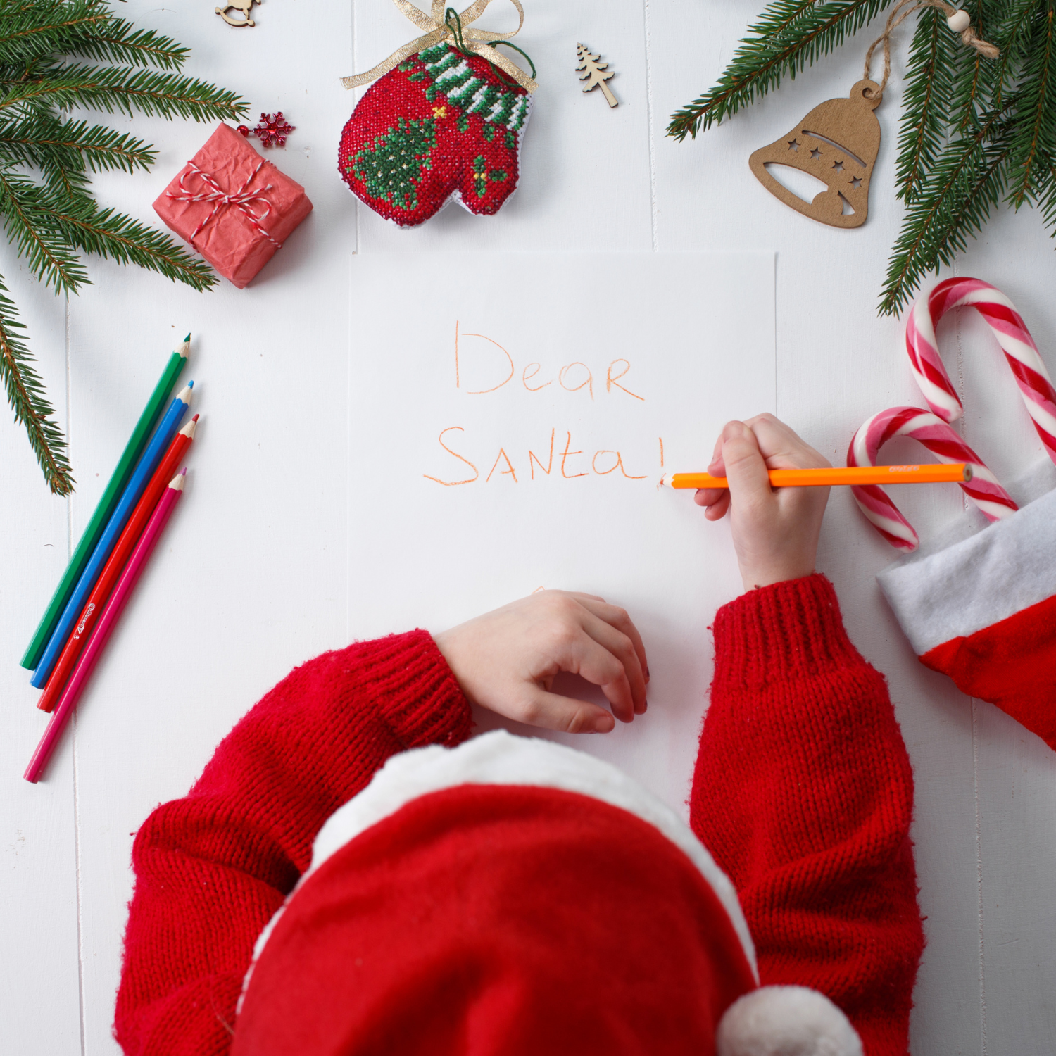 Young child wearing a red Santa hat writing a letter to Santa | Family Christmas - Clair de Lune UK