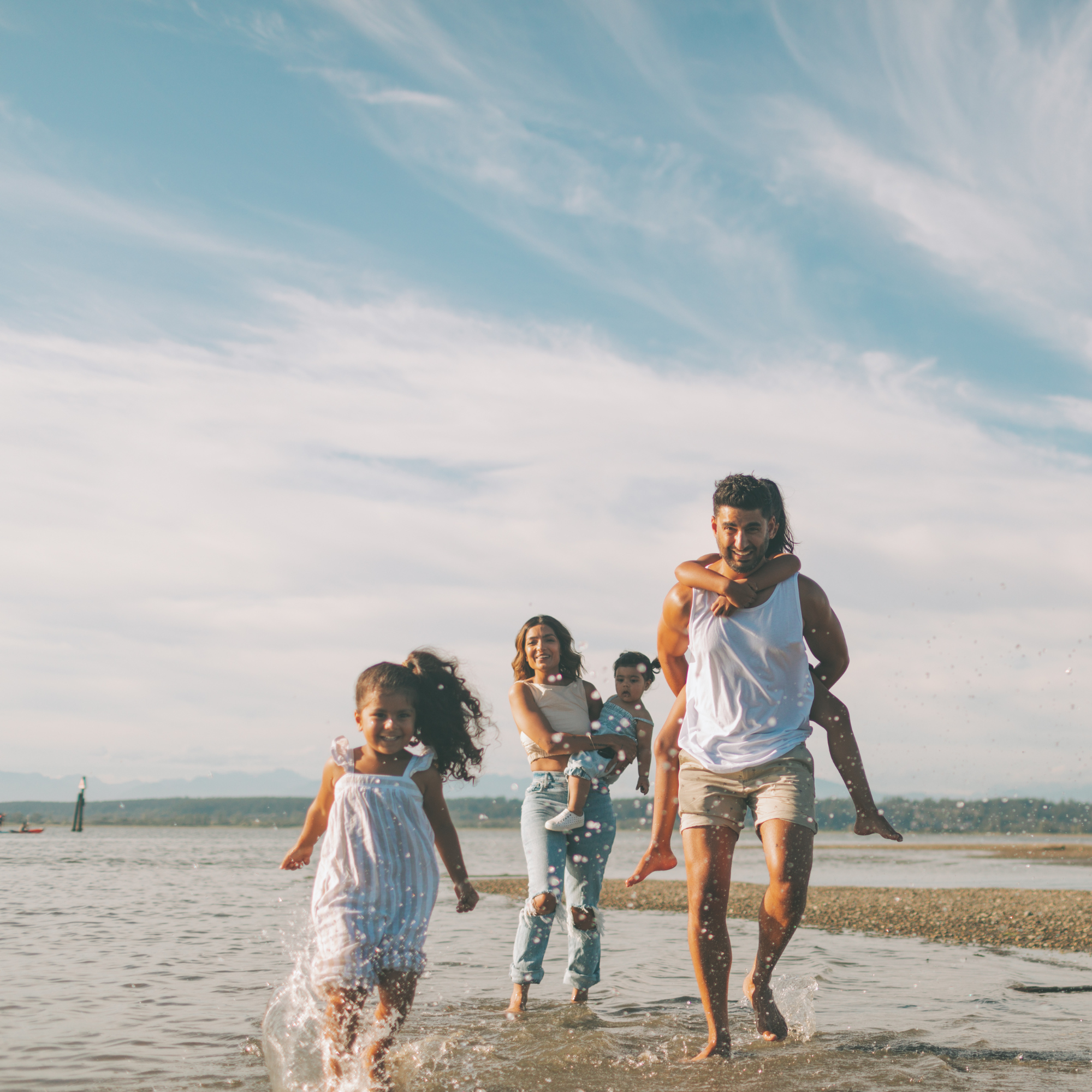 Mum and two daughters splashing in the sea at the beach | Family Holidays | Staycation UK - Clair de Lune UK