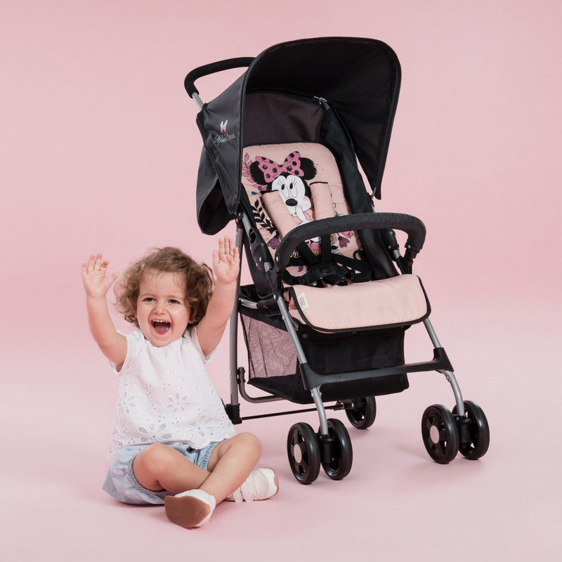 Toddler sitting next to her pink Minnie Sweetheart Hauck Disney Sport Pushchair | Strollers, Pushchairs & Prams | Pushchairs, Carrycots & Car Seats Baby | Travel Essentials - Clair de Lune UK