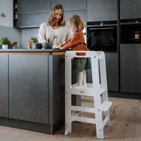 Mum cooking with her daughter who is standing on the White Universal Hauck Learn N Explore Montessori Kitchen Helper & Learning Tower | Montessori Activities For Babies & Kids - Clair de Lune UK