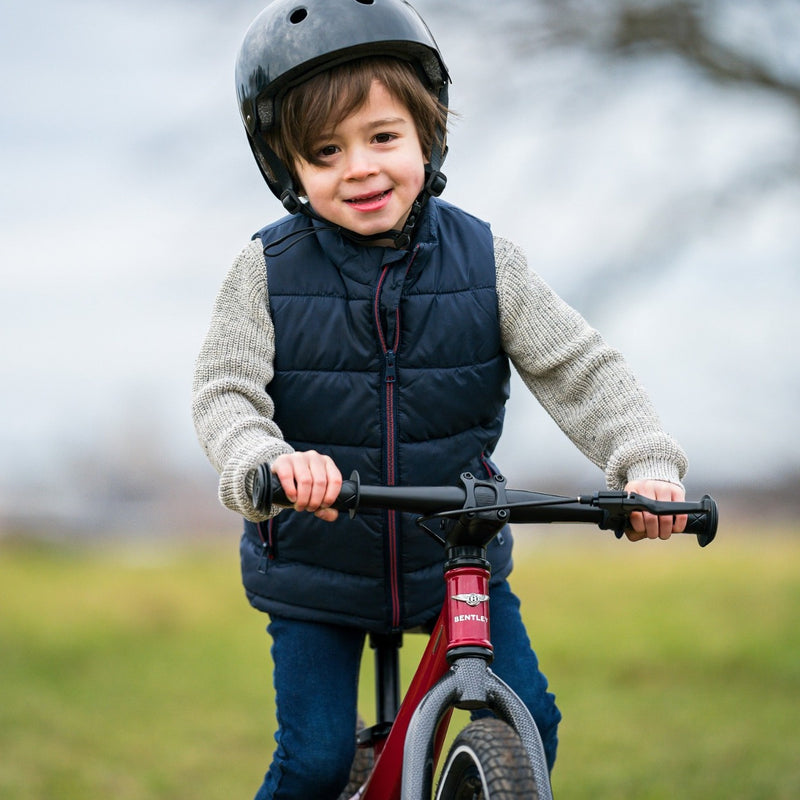 Kid enjoying riding his Dragon Red Bentley Balance Bike in the English countryside | Toddler Bikes | Montessori Activities For Babies & Kids - Clair de Lune UK