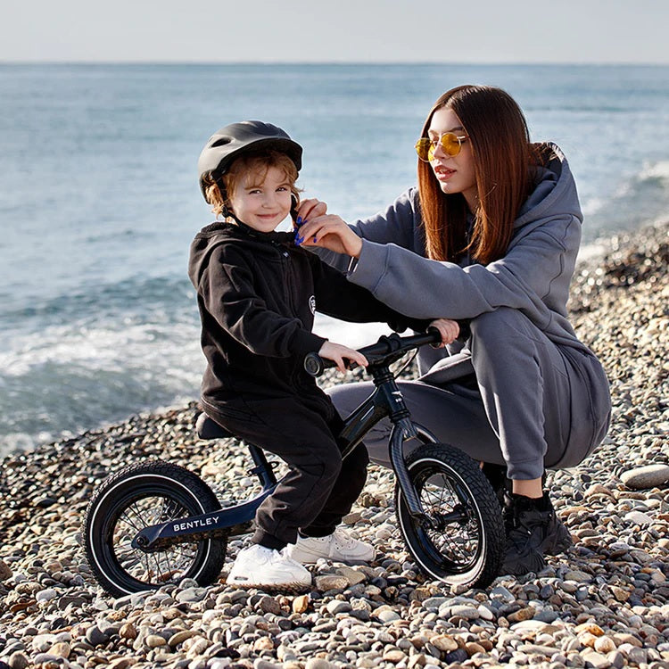 Mum checking her son's helmet while her son is on his Onyx Black Piano Black Bentley Balance Bike | Toddler Bikes | Montessori Activities For Babies & Kids - Clair de Lune UK