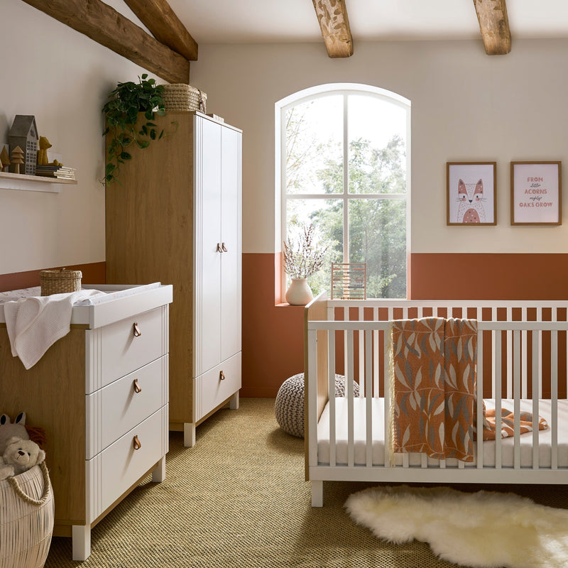 The 3-Piece Room Set including a white and natural cot bed, a matching double wardrobe and a matching dresser from the White and Natural CuddleCo Rafi Nursery Room Sets in a Biritsh countryside cottage nursery room | Nursery Furniture Sets | Room Sets | N