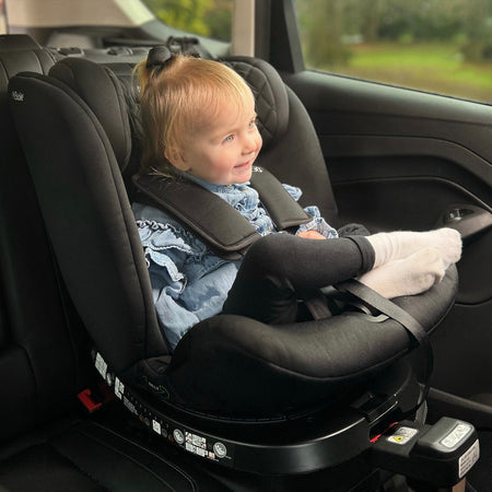 Baby sitting on the My Babiie Billie Faiers iSize Quilted Black Spin Car Seat (40-150cm) | Baby, Toddler & Kid Car Seats | Travel With Baby - Clair de Lune UK