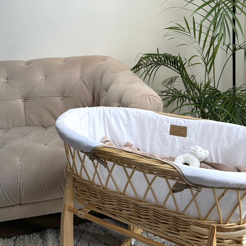 White Organic Natural Wicker Moses Basket on the Natural Rocking Stand next to a sand living room sofa | Moses Baskets | Co-sleepers | Nursery Furniture - Clair de Lune UK