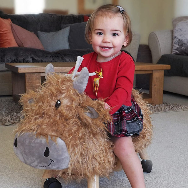 Little girl enjoying riding her Little Bird Told Me Hubert Highland Cow Ride On Toy | Baby Walkers and Ride On Toys | Montessori Activities For Babies & Kids | Toys | Baby Shower, Birthday & Christmas Gifts - Clair de Lune UK