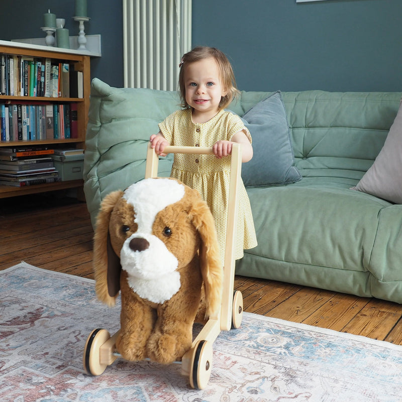 Girl pushing the Little Bird Told Me Peanut Pup 2in1 Push Along, Baby Walker and Ride On in a traditional Cotswold cottage | Baby Walkers and Ride On Toys | Montessori Activities For Babies & Kids | Toys | Baby Shower, Birthday & Christmas Gifts - Clair d