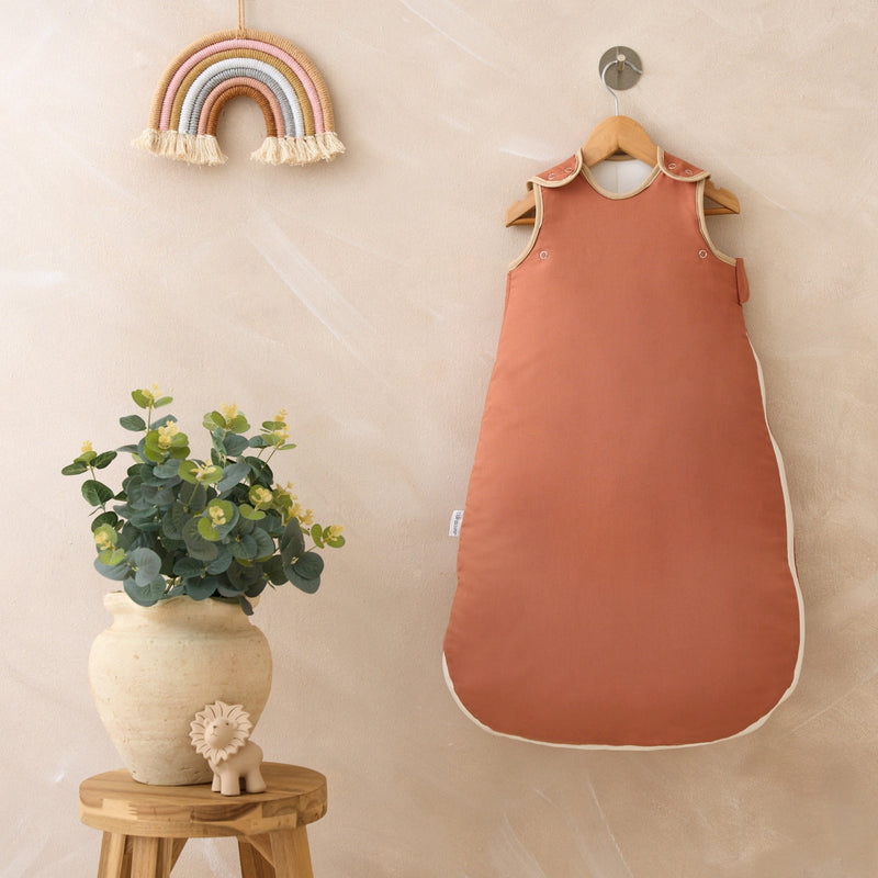 Rust Orange Organic Sleeping Bag (0-6 Months) on a wall-mount hanger in a Scandi nursery | Baby Sleep Bags, Shawls, Swaddles & Sleepbags | Nightwear | Nursery - Clair de Lune UK