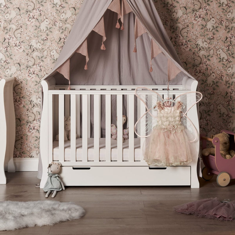 The cot bed of the white Obaby Stamford Mini Sleigh Cot & Changing Unit in a pink princess nursery room | Nursery Furniture Sets | Room Sets | Nursery Furniture - Clair de Lune UK