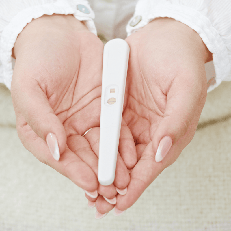 Hands creating a heart shape holding a positive pregnancy test | Pregnancy tips and advice - Clair de Lune UK