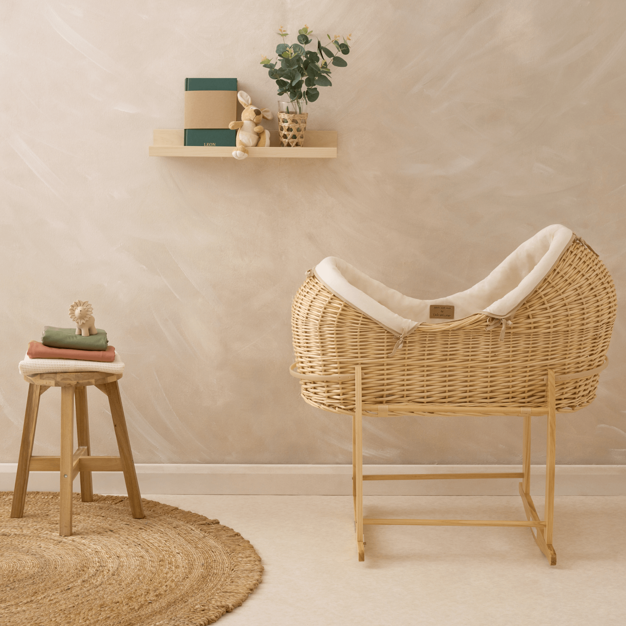 Organic Natural Noah Pod with cream bedding in front of a limewashed wall on a natural deluxe rocking stand | Sustainable baby bedding - Clair de Lune UK