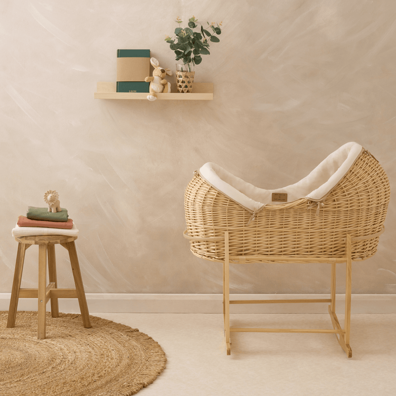 Organic Natural Noah Pod with cream bedding in front of a limewashed wall on a natural deluxe rocking stand | Sustainable baby bedding - Clair de Lune UK