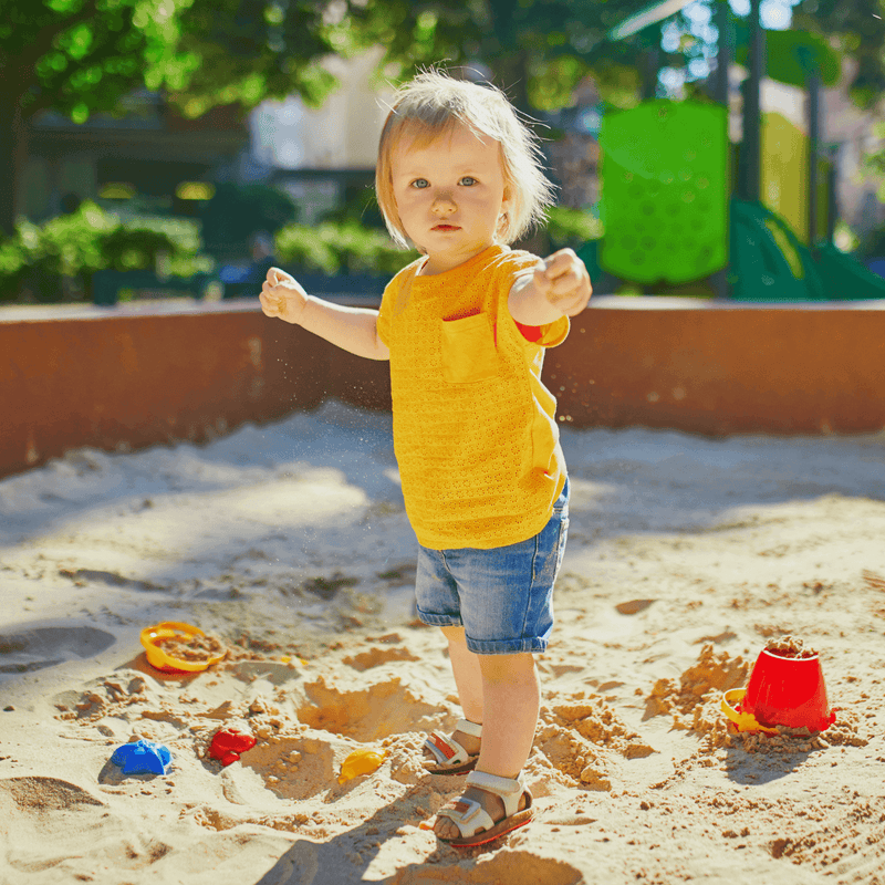 Toddler wearing shorts and t-shirt playing in the sandpit on a sunny summer day | 15 Free Outdoor Activities for Toddlers This Summer - Clair de Lune UK