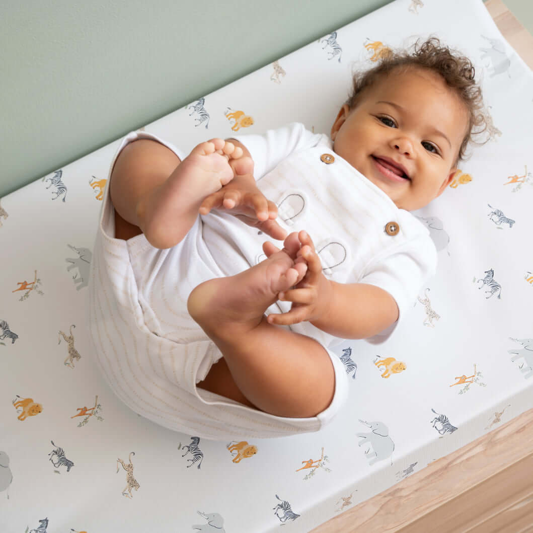 Happy baby holding their toes on the Clair de Lune Jungle Dream Anti-Roll Wedge Changing Mat