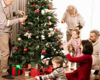 Family with two children decorating the christmas tree with white and red decorations | Family Christmas - Clair de Lune UK