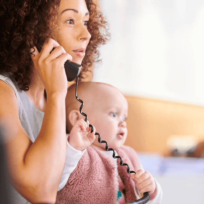 Baby sat on mum's knee while she's working and on the phone | Parenting tips and advice - Clair de Lune UK