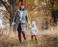 Mum and toddler girl wrapped up in coats and hats holding hands, walking down a path with autumn leaves and trees | News - Clair de Lune UK