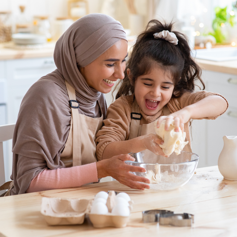 Mum wearing a hijab and her daughter baking at the kitchen island | Toddler Activities - Clair de Lune UK