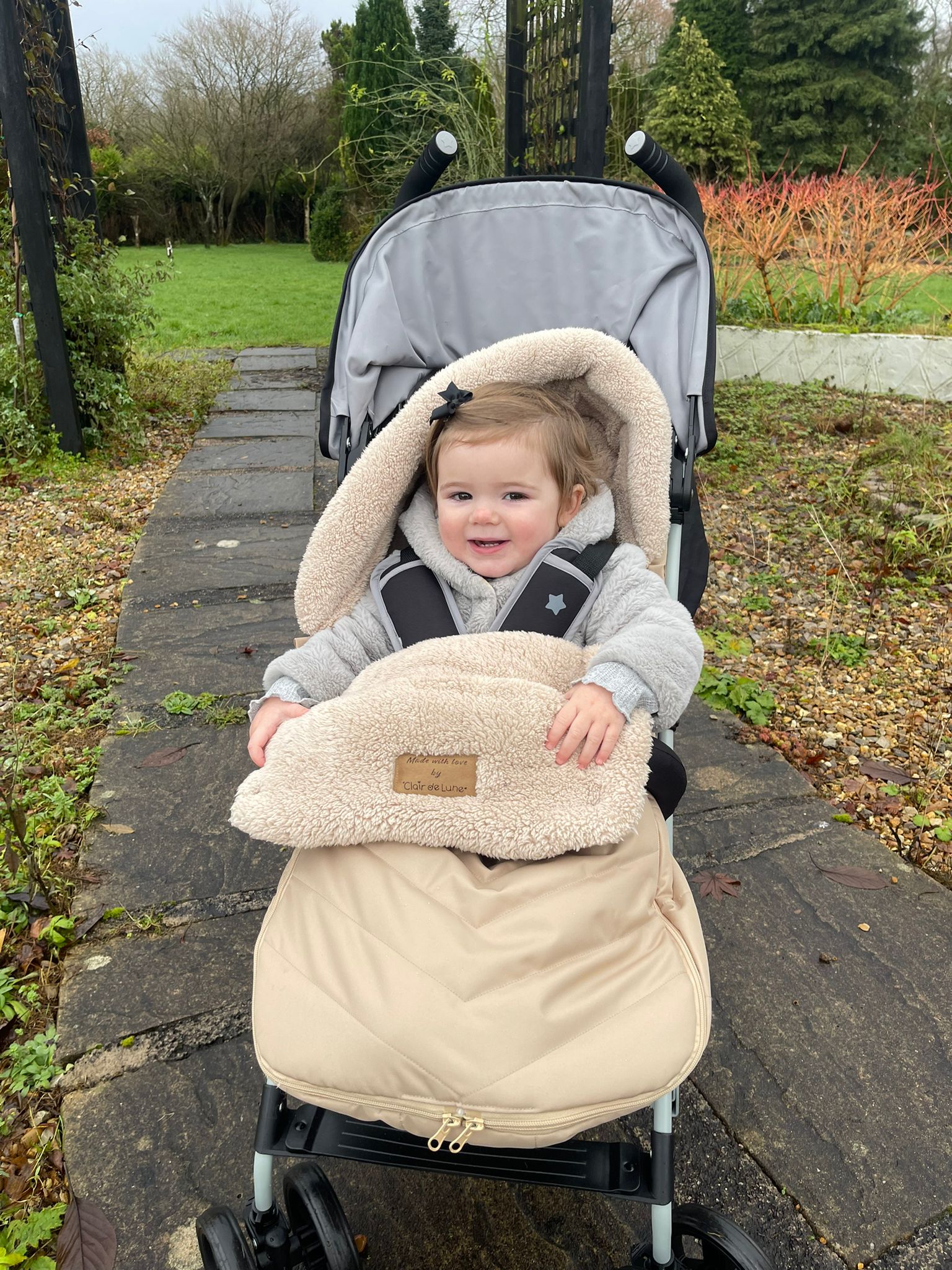 Baby girl in Beige Snug footmuff enjoying a stroll in the park | Pushchair Accessories - Clair de Lune UK