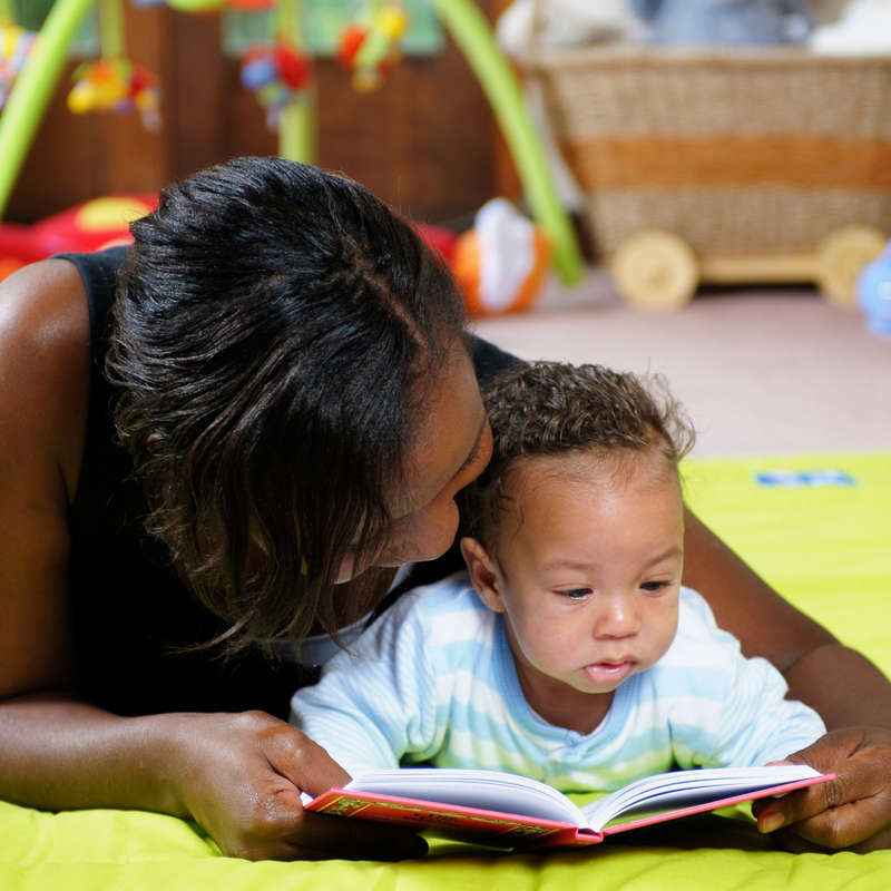 Mum and baby lying on the floor reading a book | Child development - Clair de Lune UK