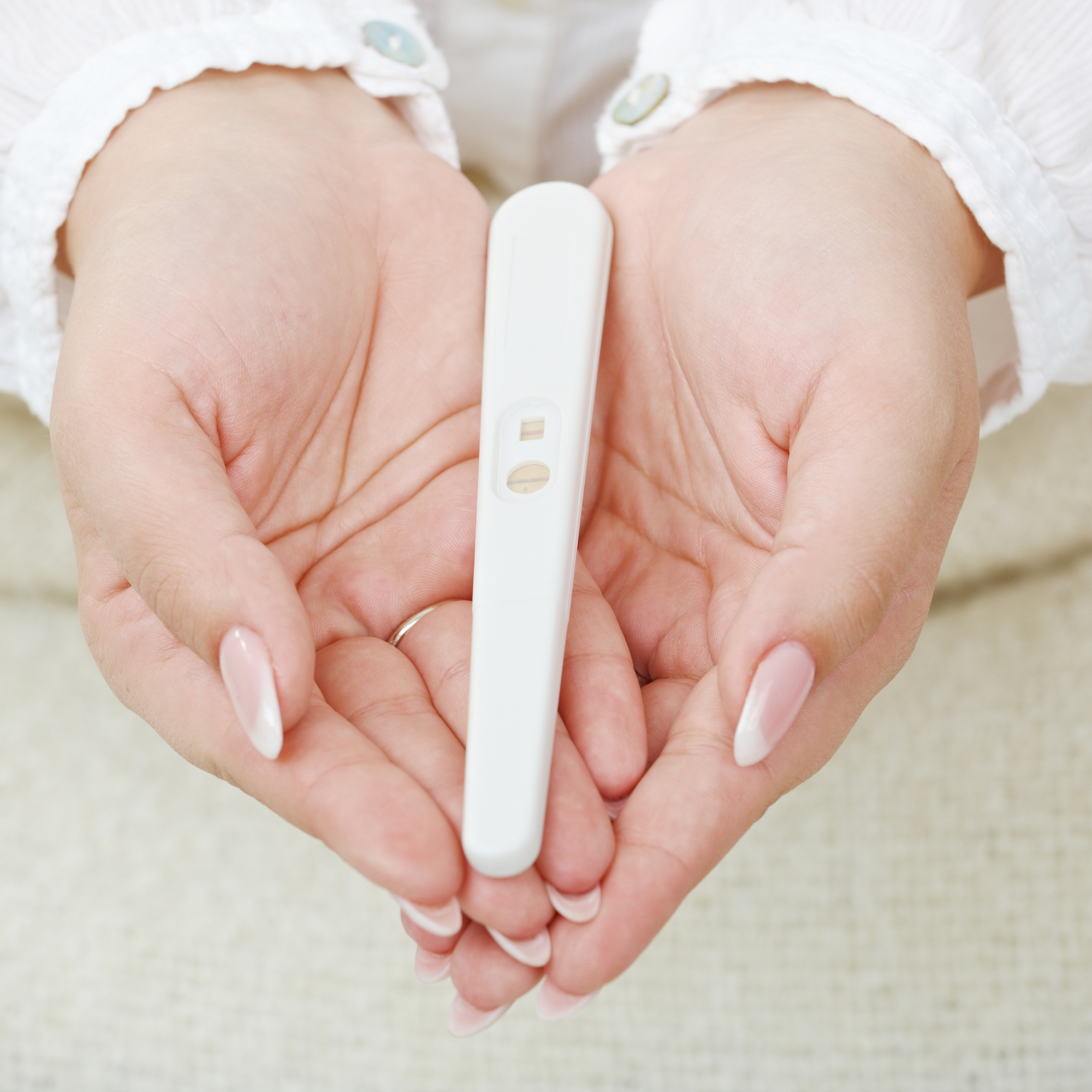Hands creating a heart shape holding a positive pregnancy test | Pregnancy tips and advice - Clair de Lune UK