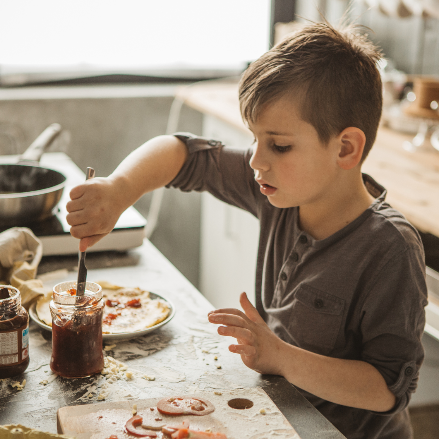 Boy at the dining table adding chocolate to his homemade pancake | Family Time - Clair de Lune UK