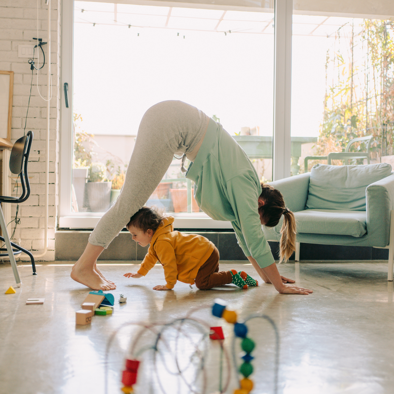 Mum wearing gym gear doing yoga in the living while her toddler plays next to her | Parenting tips and advice - Clair de Lune UK