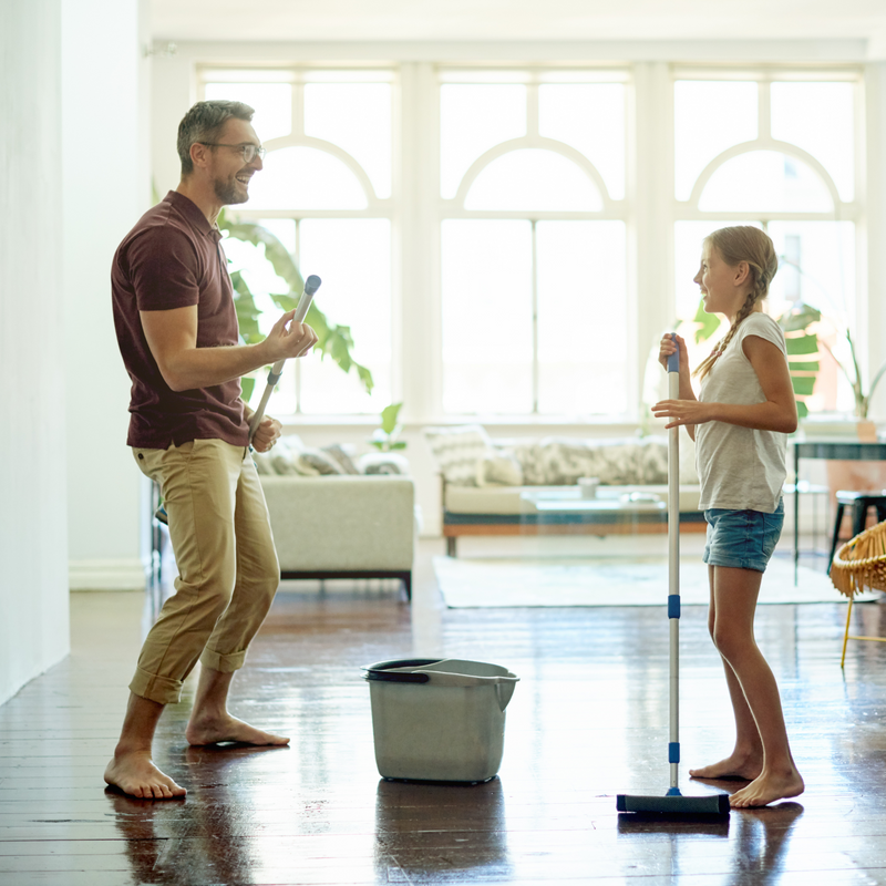 Dad and daughter dancing and singing into their mops as they clean the kitchen | Spring cleaning | Parenting tips and advice - Clair de Lune UK