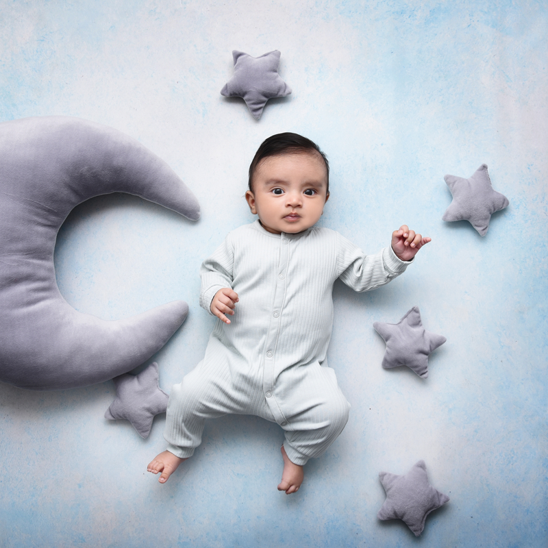 Baby boy wearing a white onesie surrounded by grey star and moon cushions | Parenting tips and advice - Clair de Lune UK