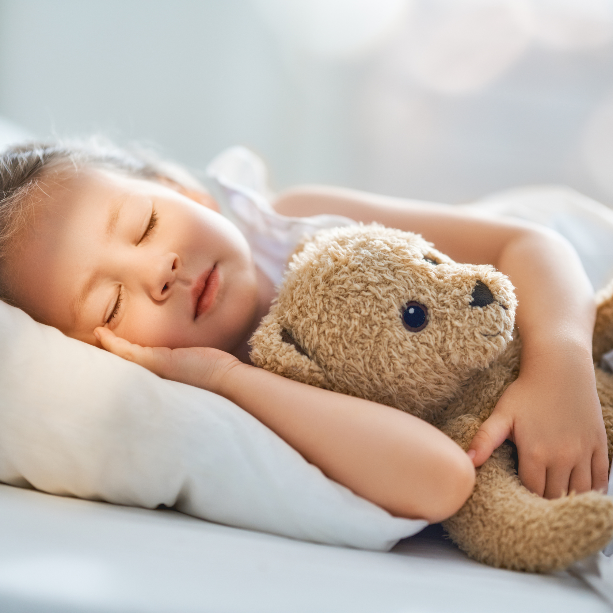 Girl lying asleep on a pillow in bed with her teddy bear | Parenting tips and advice - Clair de Lune UK