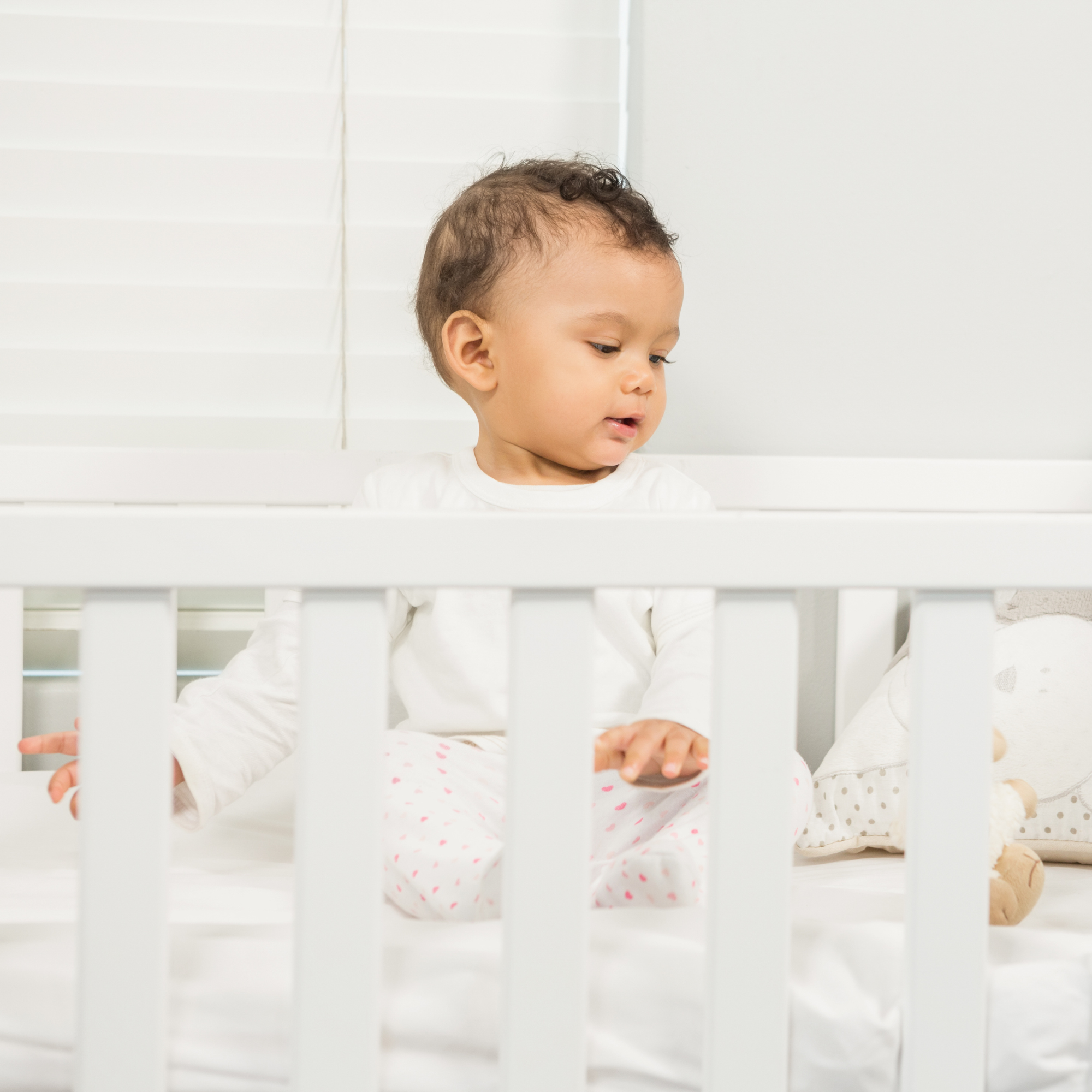 Toddler sitting up in a white cot bed | Parenting tips and advice - Clair de Lune UK