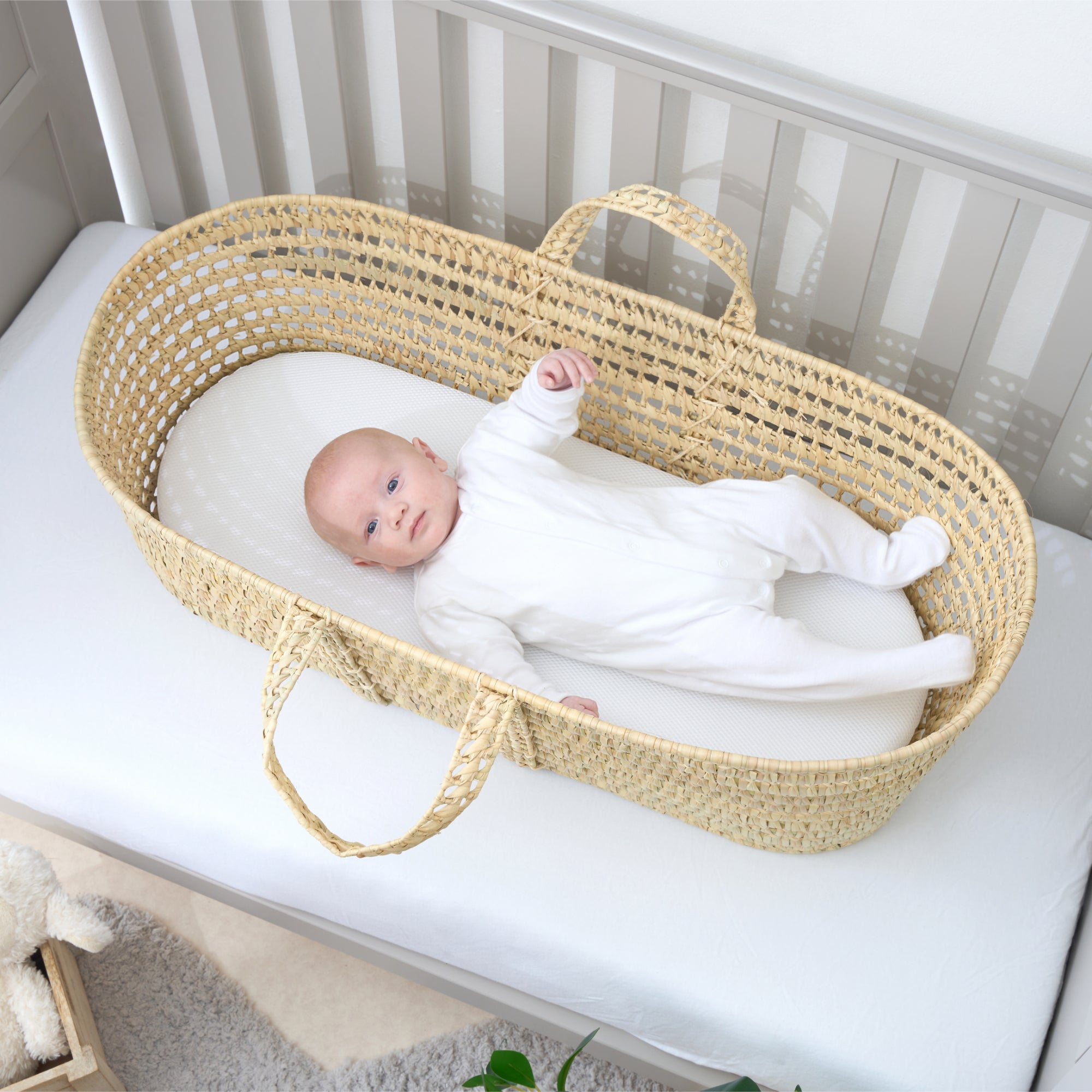 Newborn baby boy lying in an undressed palm Moses basket lying on a hypoallergenic palm moses basket mattress | Nursery Essentials - Clair de Lune UK