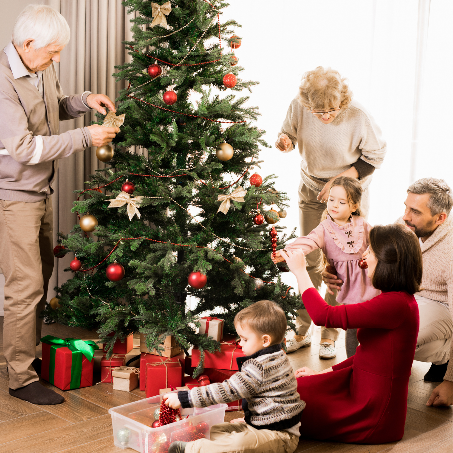 Family with two children decorating the christmas tree with white and red decorations | Family Christmas - Clair de Lune UK