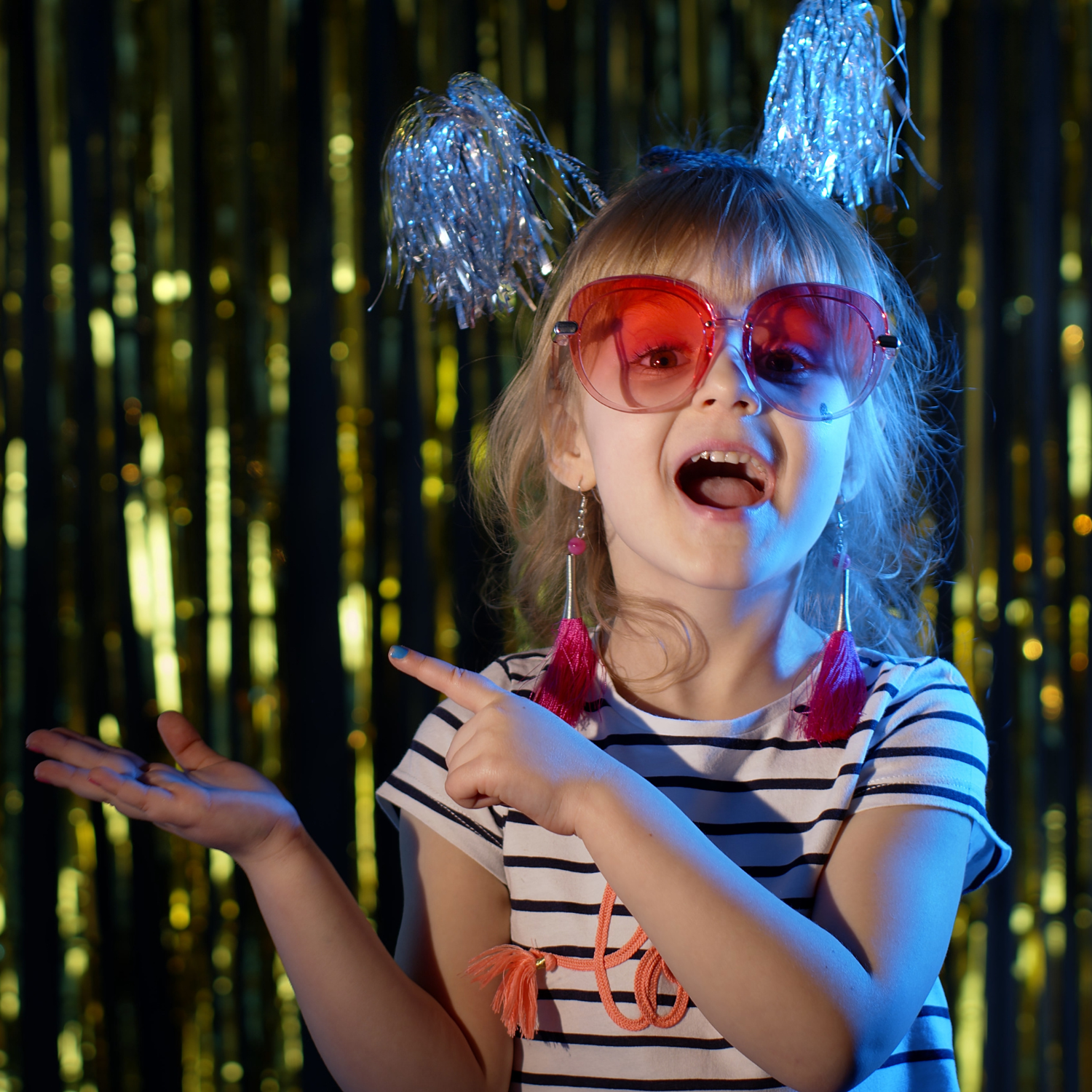 Young girl dressed in striped shirt and sunglasses and wearing streamers and party hat at a party | Family New Year - Clair de Lune UK