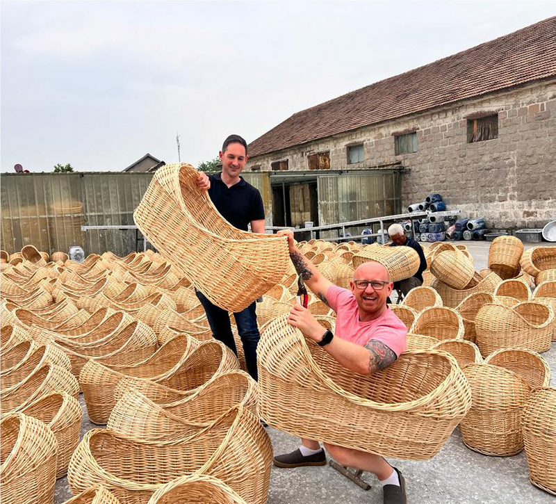 Guy and Hadley in the Clair de Lune factory holding all the wicker Noah Pods - Clair de Lune UK