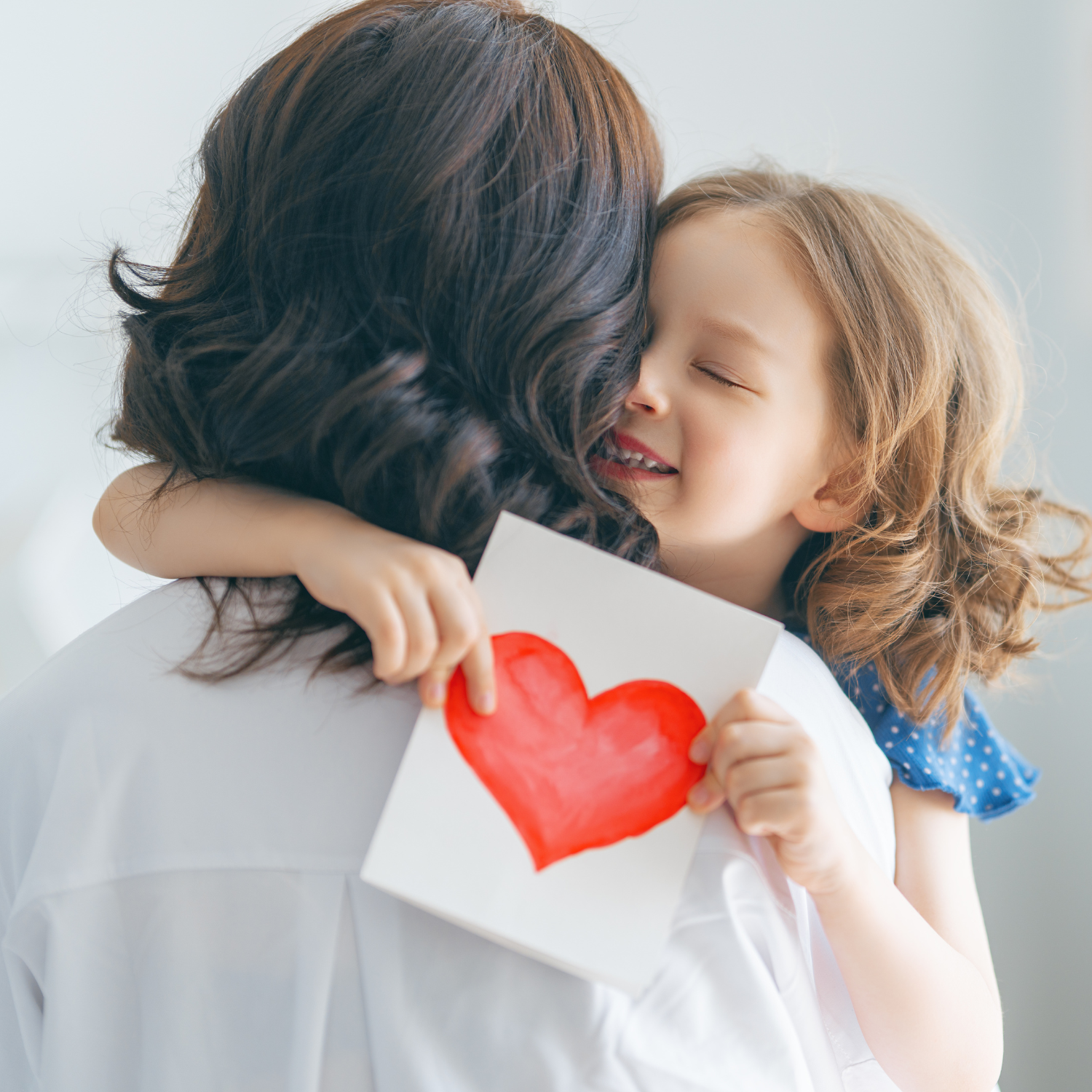 Girl hugging mum tightly while holding DIY heart card | Mother's Day - Clair de Lune UK