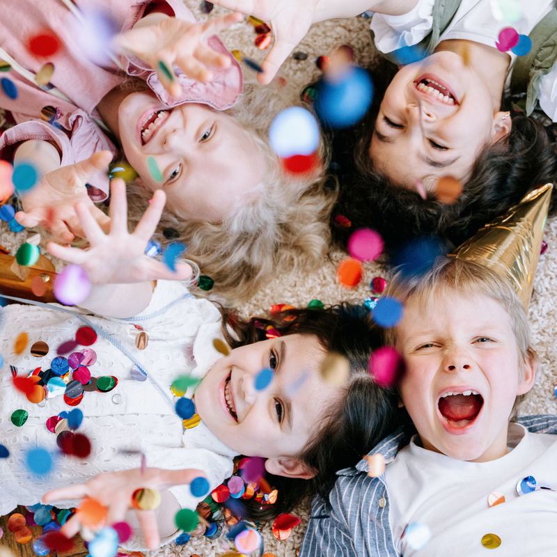 Family of four throwing new year's confetti while looking at the camera | Family New Year - Clair de Lune UK