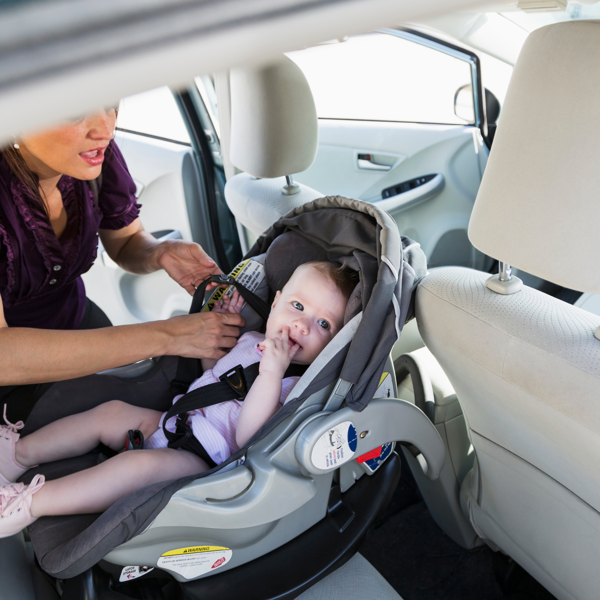Mum placing son in a rear facing car seat | Summer Safety | Car Seat Safety - Clair de Lune UK