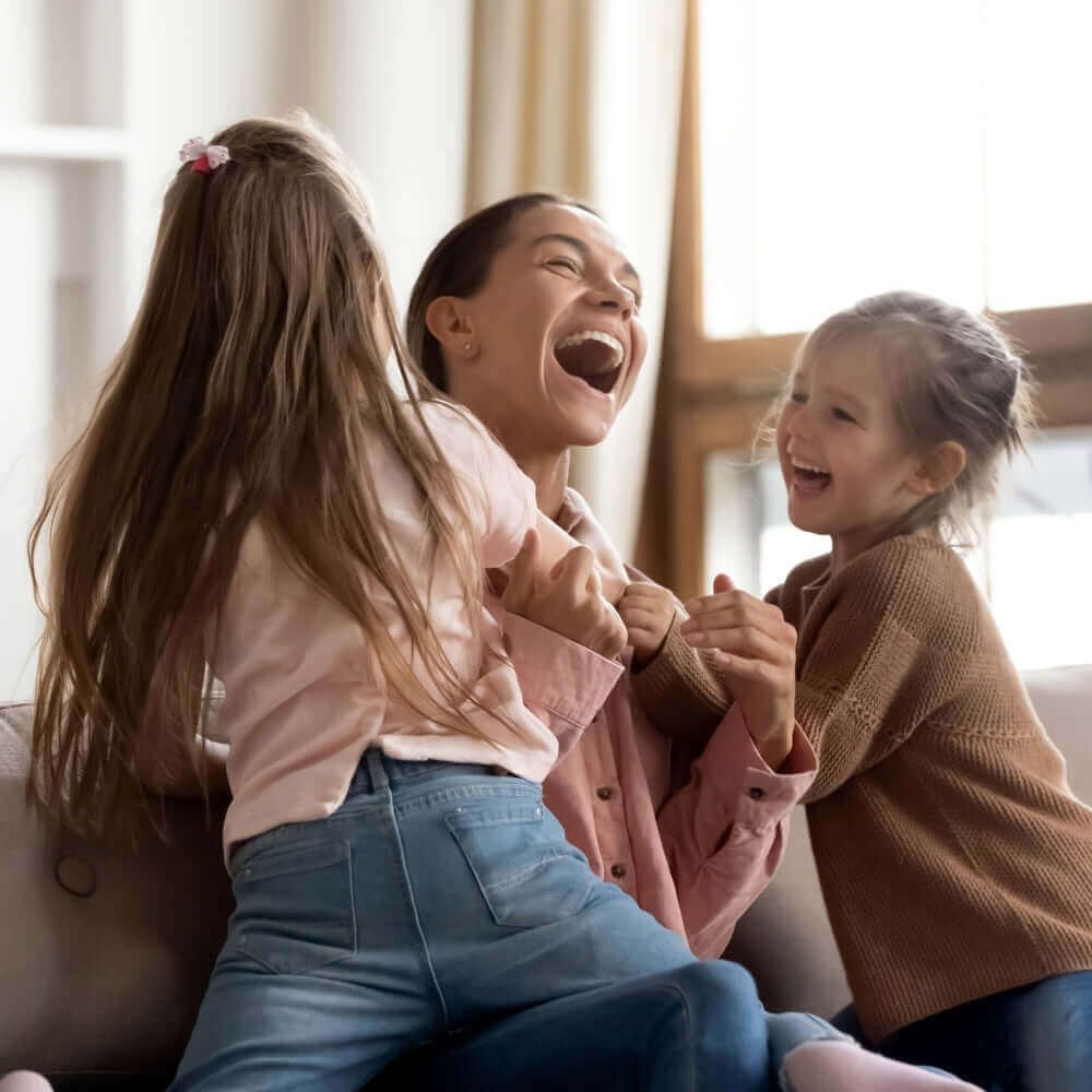 Mum laughing and hugging her children | The Reality of Mother’s Day with Little Ones: Expectation vs Reality | Parenting & Buying Guides - Clair de Lune UK