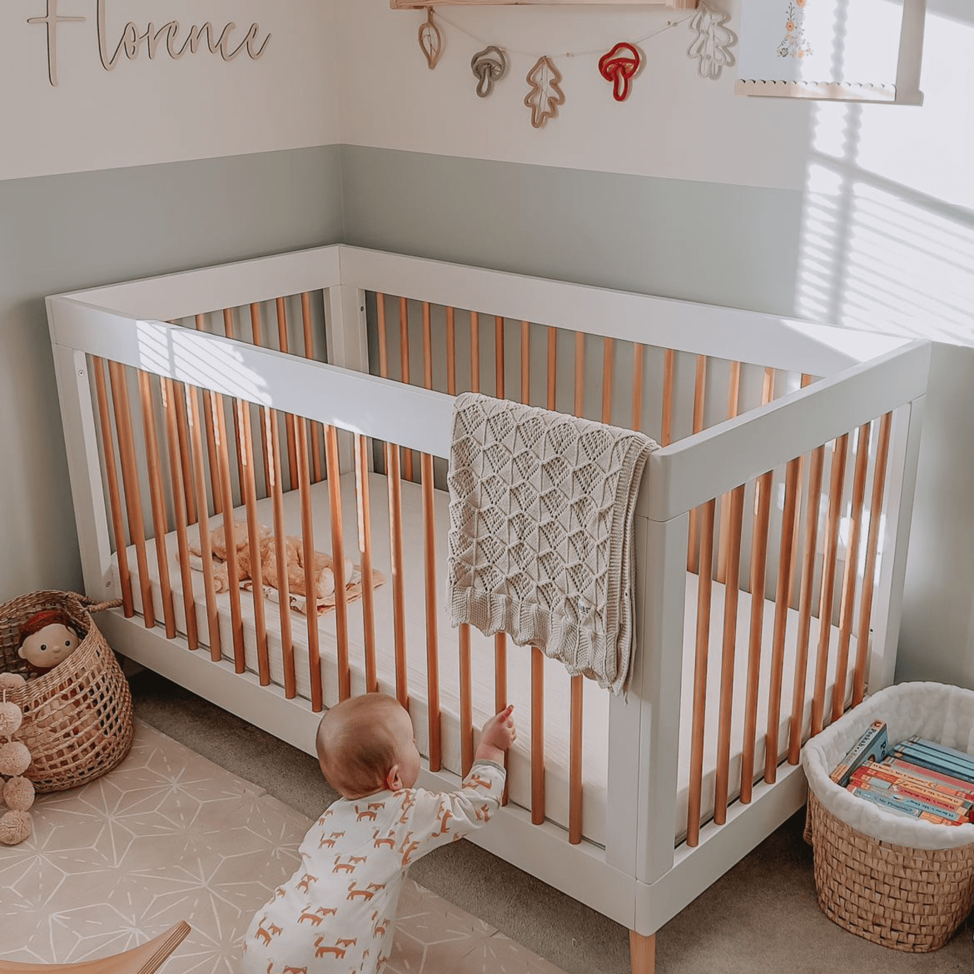 Baby crawling next to the cot bed in their scandi style nursery | Parenting tips and advice - Clair de Lune UK