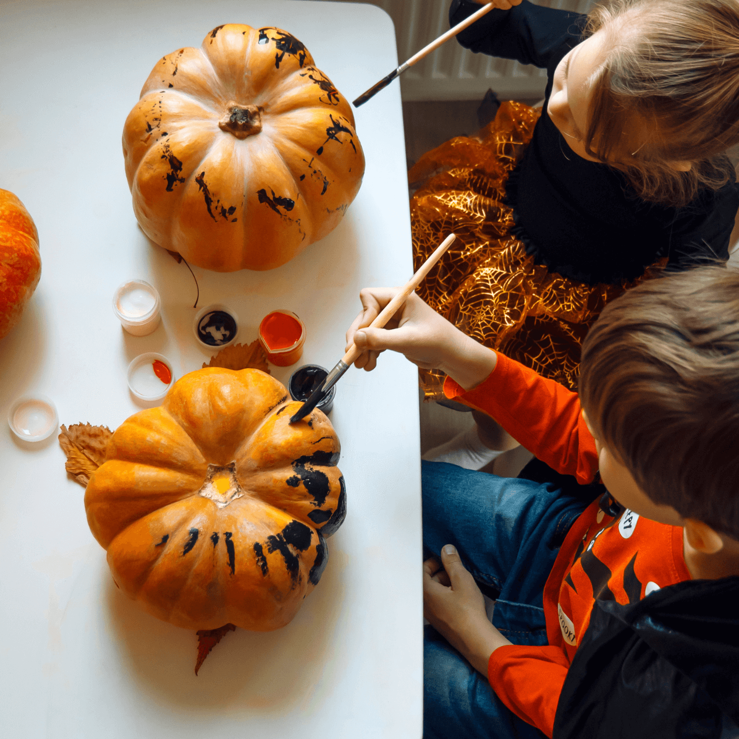 Two toddlers sat at the table painting their pumpkins | Messy Play - Clair de Lune UK