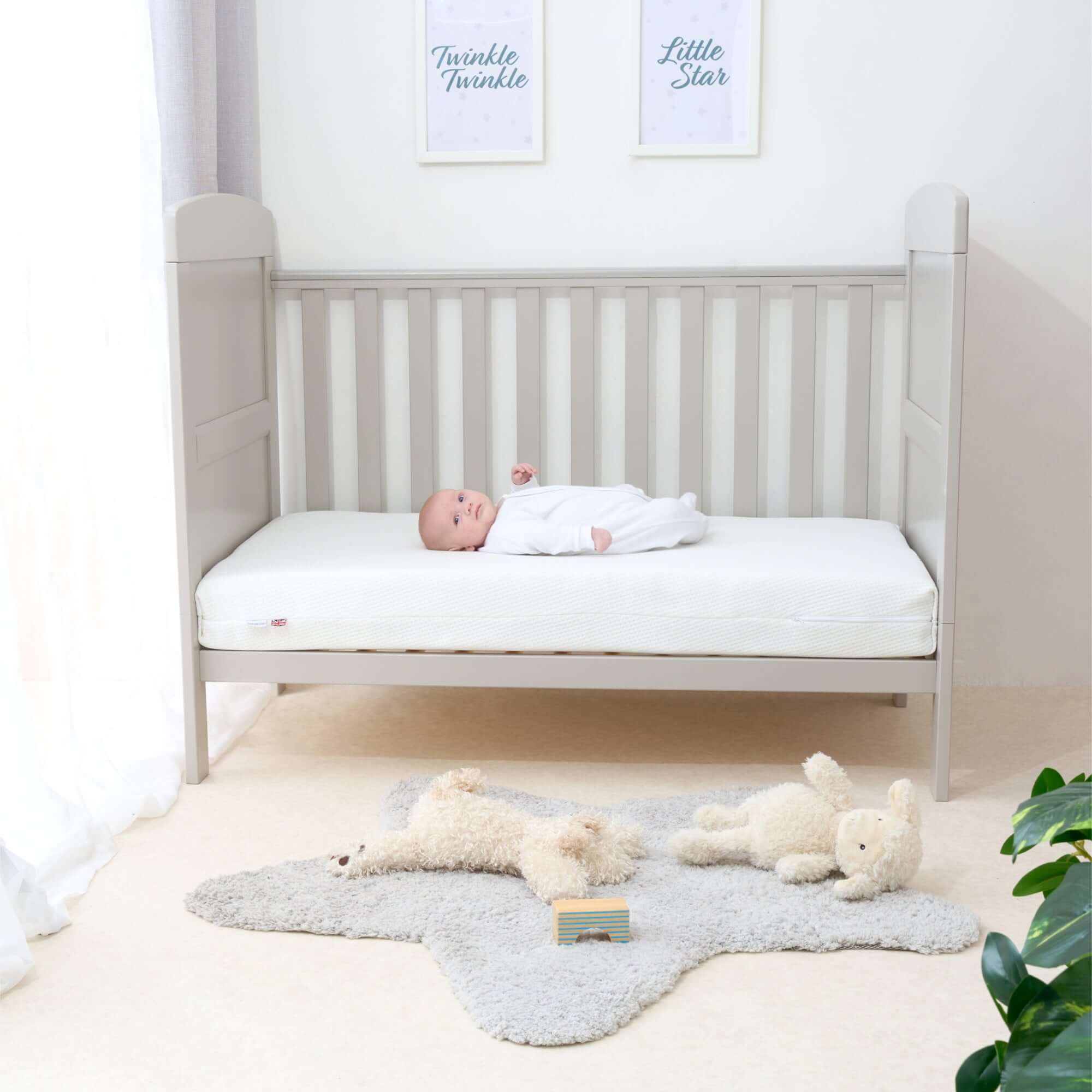 Baby boy lying on the Essentials Fibre Cot Bed Mattress in a grey nursery | Parenting tips and advice - Clair de Lune UK