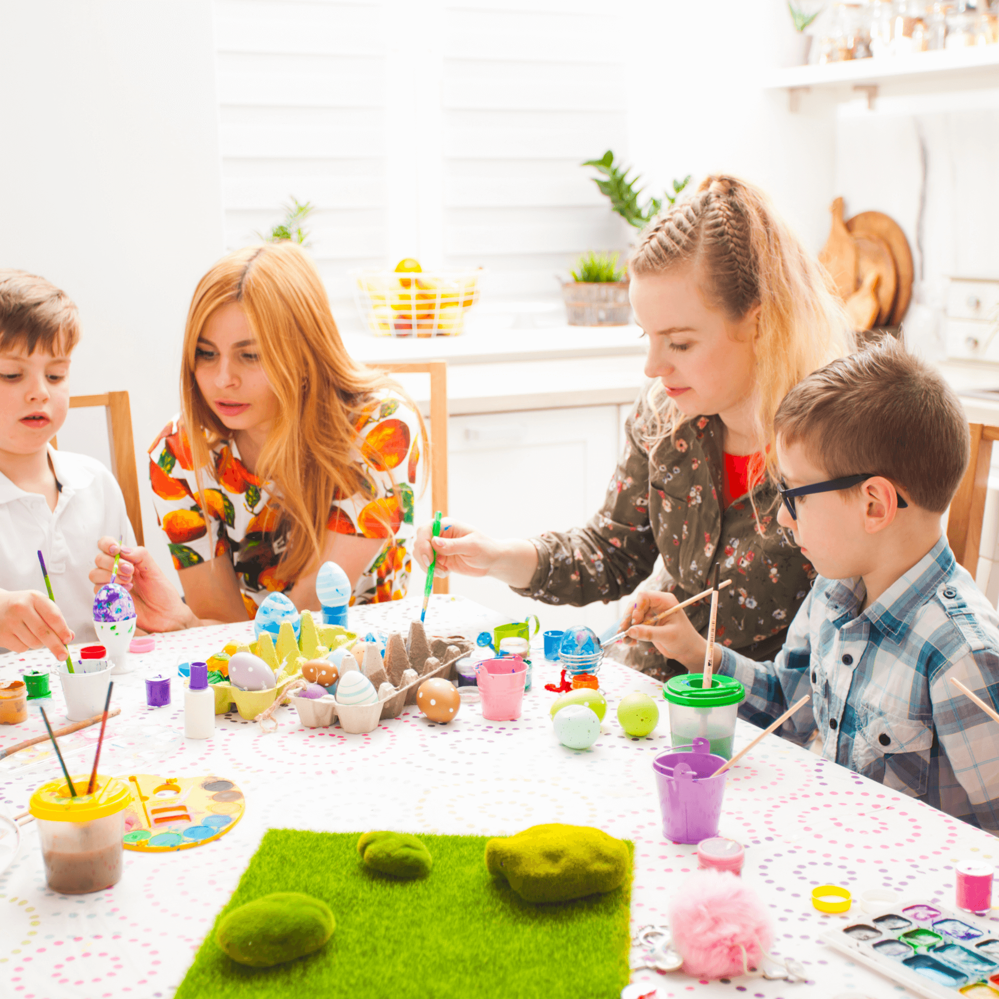 Family sat at the table with paints and paint brushes decorating easter eggs | Easter Activities | Family Time - Clair de Lune UK