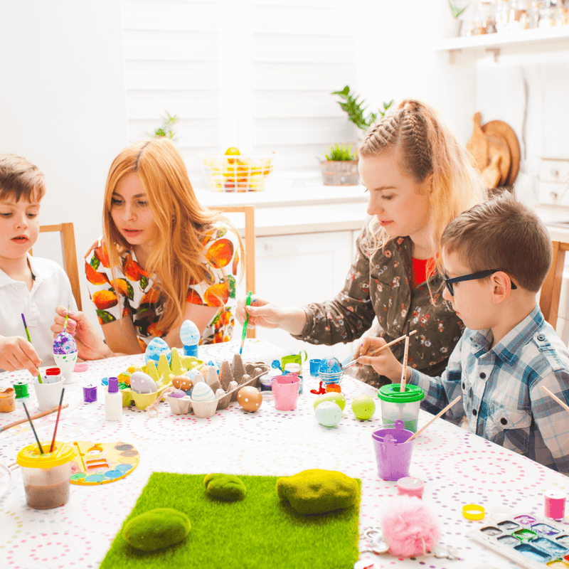 Family sat at the table with paints and paint brushes decorating easter eggs | Easter Activities | Family Time - Clair de Lune UK