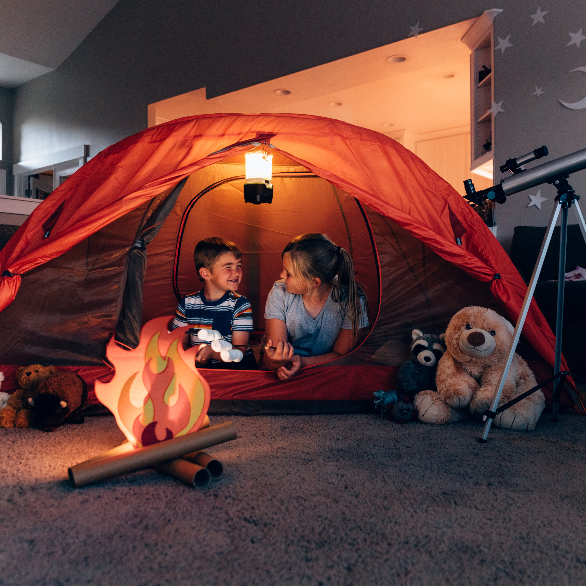 Children playing indoors in a DIY blanket fort with crafted camp fire | Family time - Clair de Lune UK
