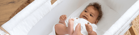 Baby playing in the White Organic Folding Crib | Nursery Furniture - Clair de Lune UK