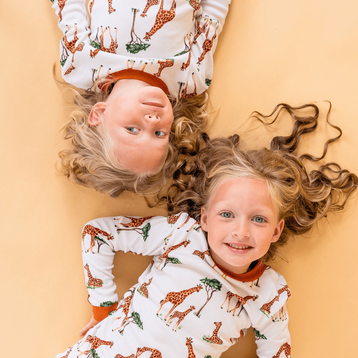 Two girls wearing matching Grow Grows Organic Gentle Giraffes Pyjamas | Organic Kids PJs and Nightwear - Clair de Lune UK