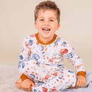 Boy sat smiling wearing the Grow Grows Organic Plentiful Planets Pyjamas | Organic Kids PJs and Nightwear - Clair de Lune UK